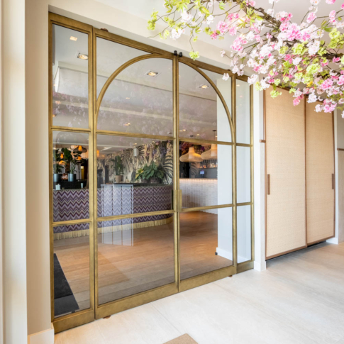 Luxe messing stalen schuifdeuren met glas en elegante boogdetails, als stijlvolle entree naar een chique interieur.